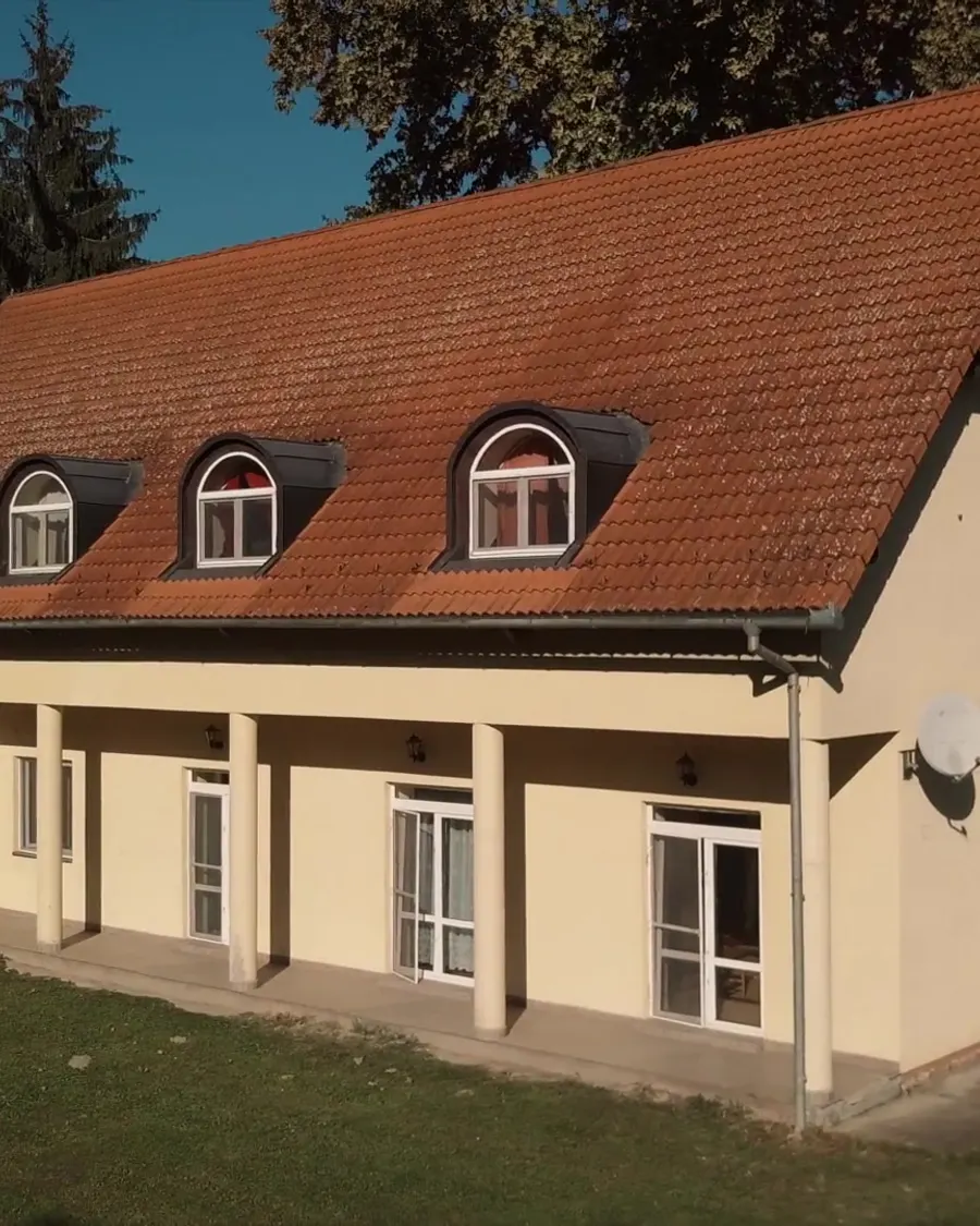 Piros tetős lakószárny íves tetőablakokkal és teraszajtókkal