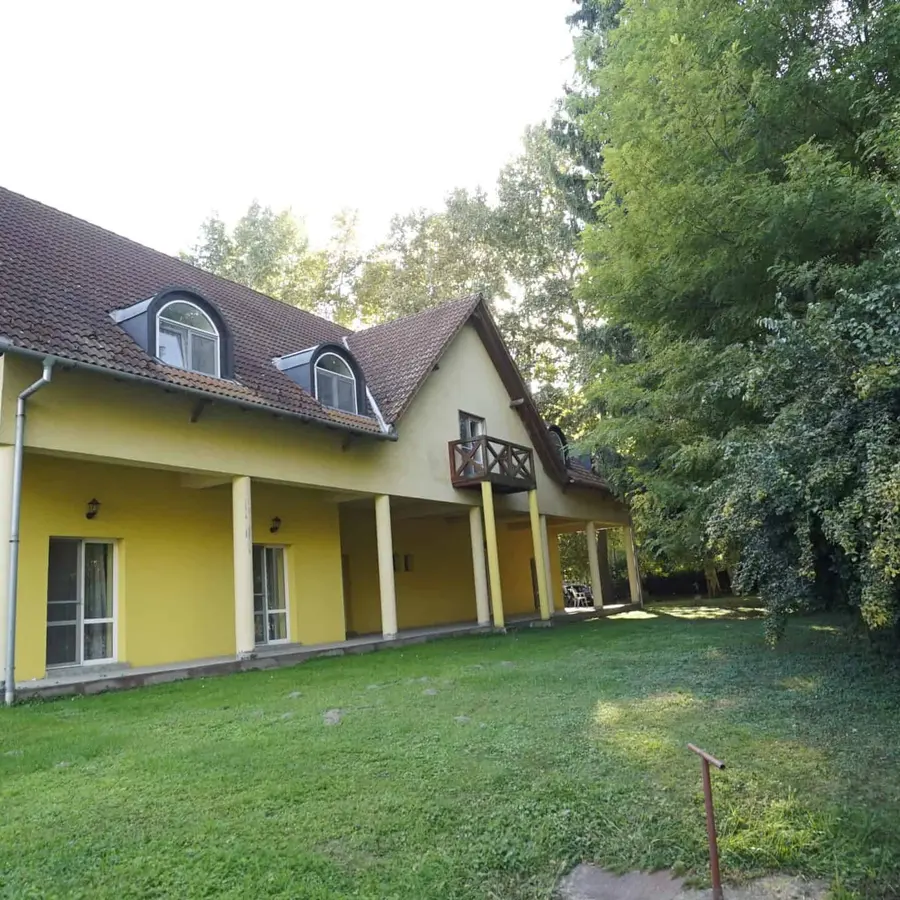 Sárga falú lakószárny teraszajtókkal a park felől