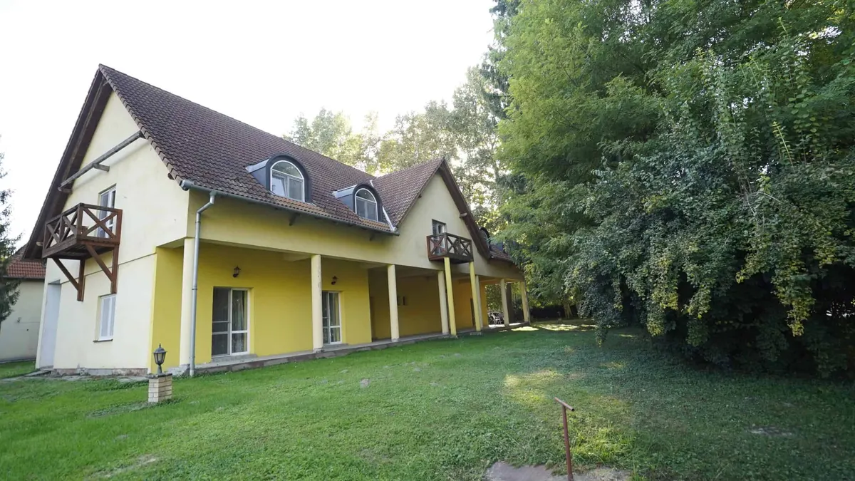 Az otthon sárga falú, tetőtér-beépítéses épületszárnya a park felől